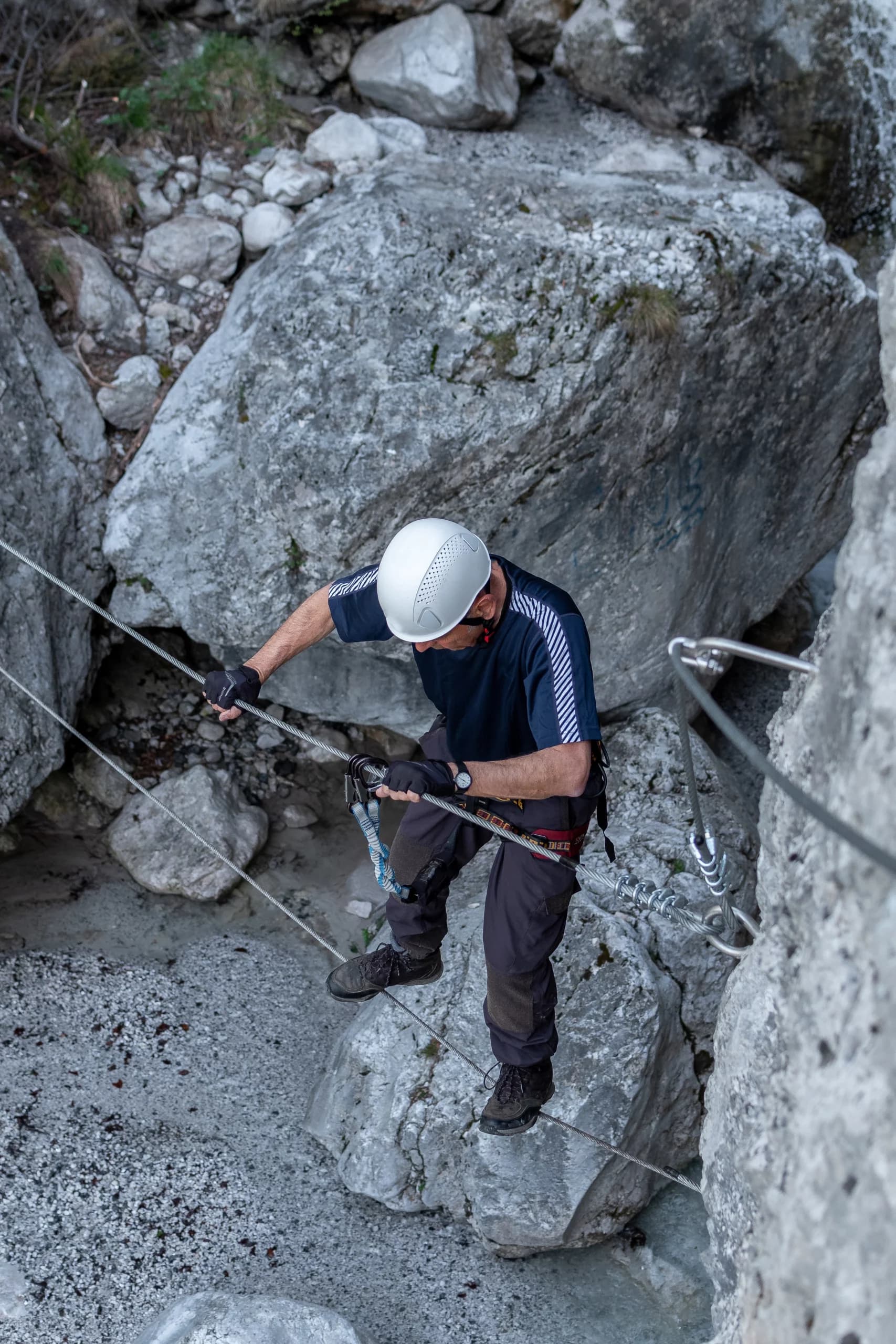 Persona equipada progresando por una vía ferrata en pared vertical